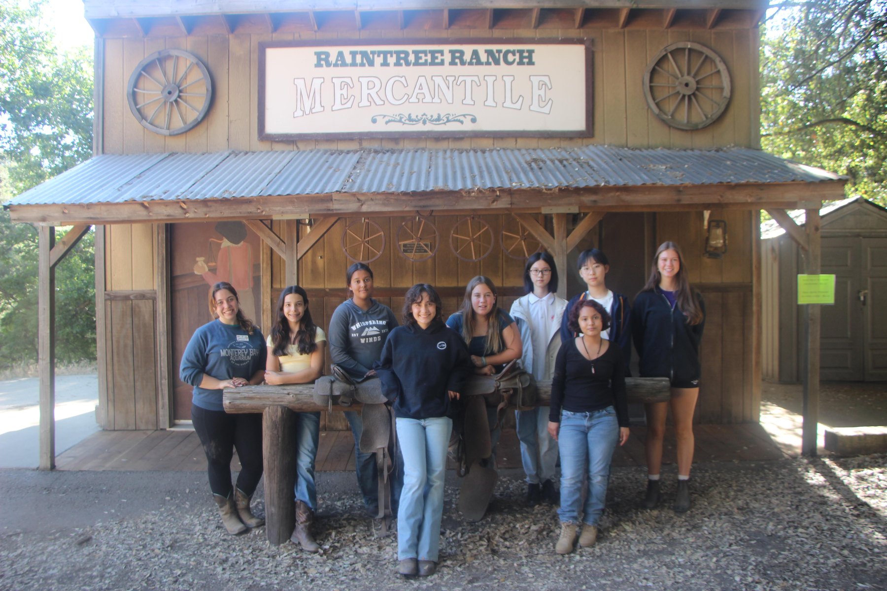 Camp participants gather for a photograph outside a wooden ranch building